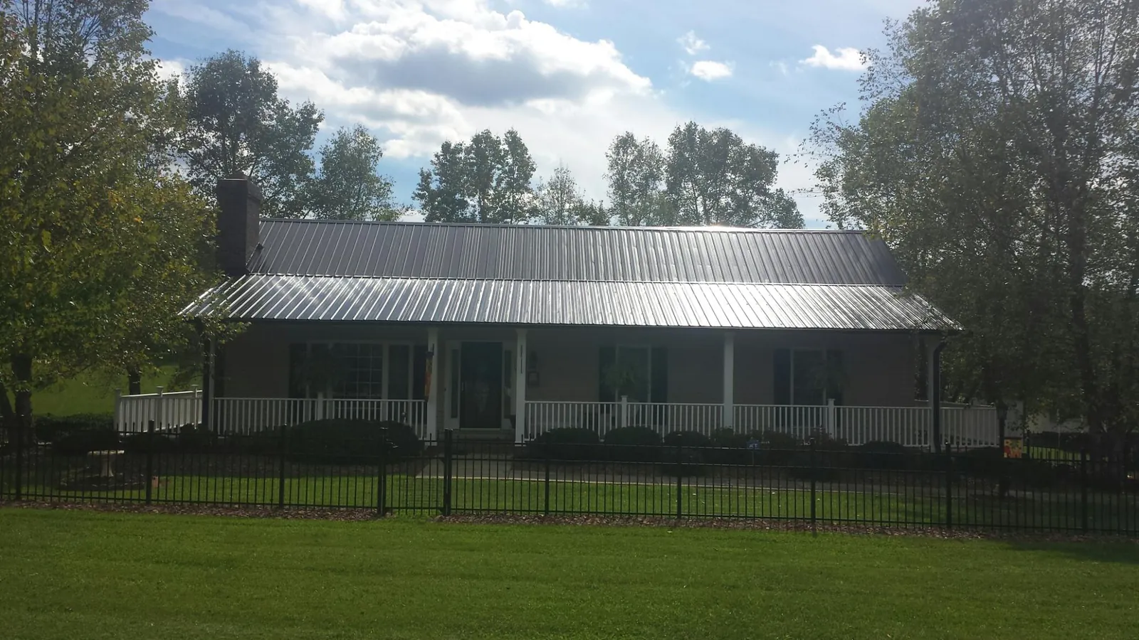 Gray metal roof on a brick ranch with a full width front porch — Gutter Guard Installation work by our crew in Maysville