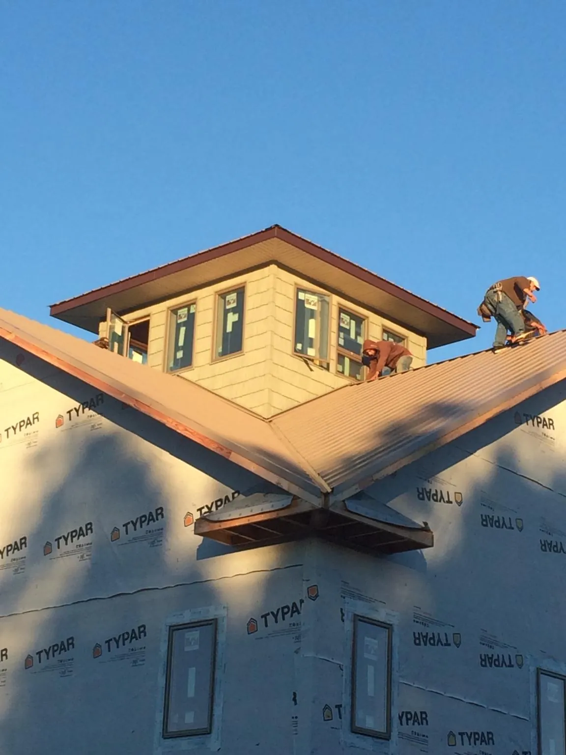 Roofers working around a rooftop cupola on a new metal roof at sunset — Roof Waterproofing in Maysville by Roofing Brothers